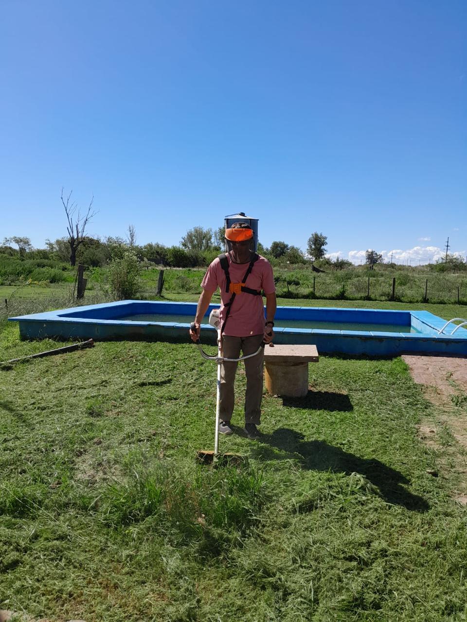 Operario con bordeadora y protección terminando el borde de una pileta